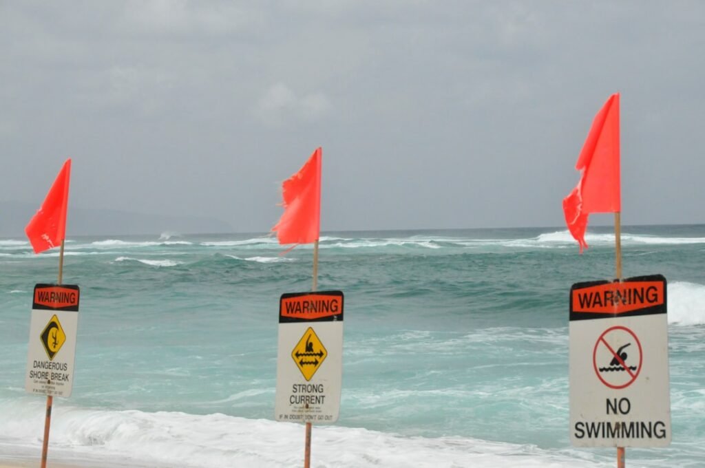 Red warning flags on beach with danger and warning signs indicating hazardous conditions