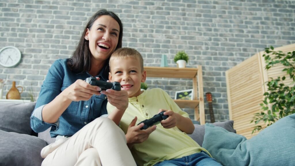 Mother and child playing video games together on couch, illustrating safe family gaming with parental supervision